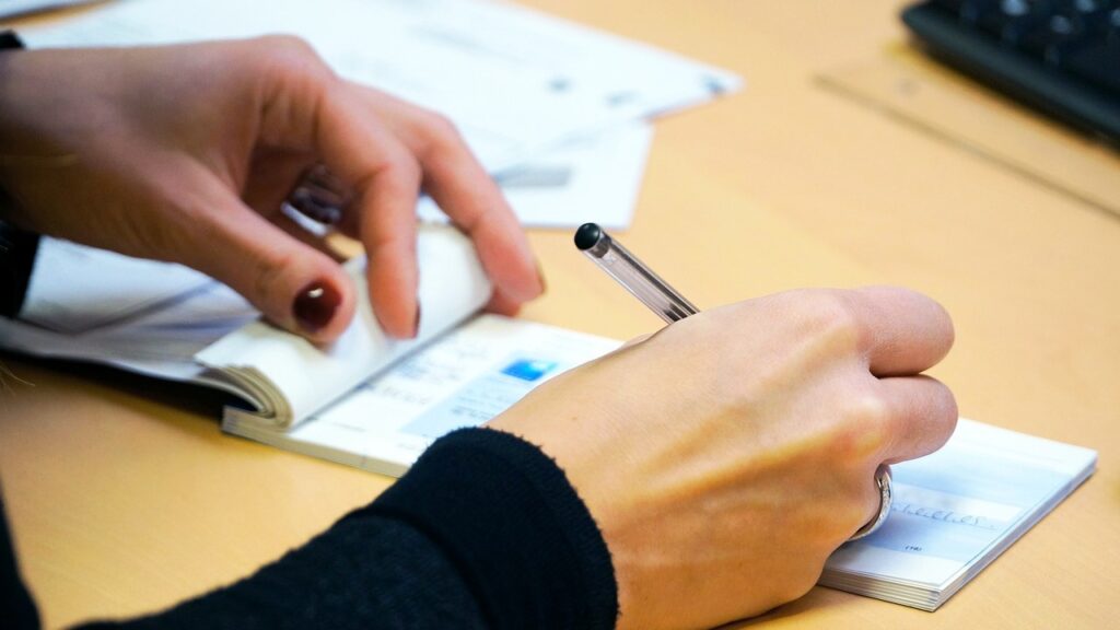 Manos de mujer con bolígrafo escribiendo un cheque