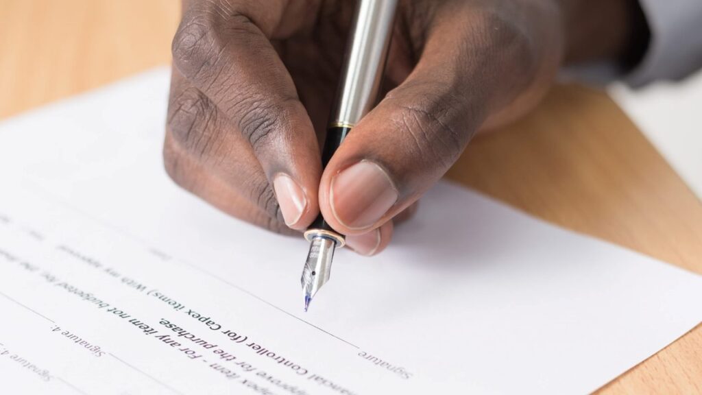 Mano firmando documento alusivo a una aprobación de que la segunda opinión médica es un derecho