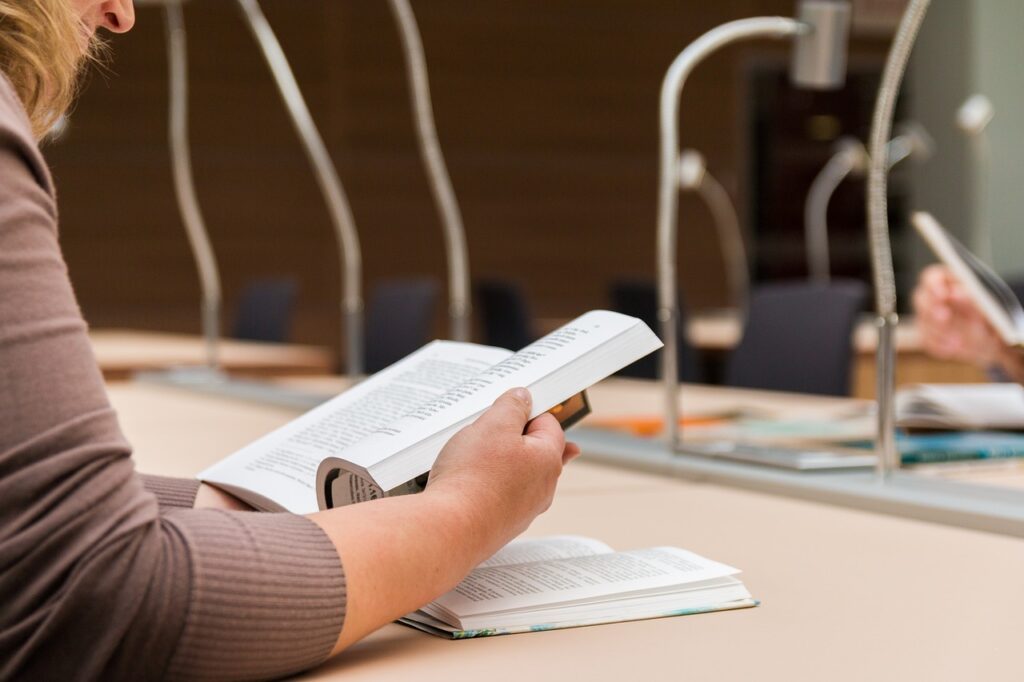 Brazo de persona con un libro alude a estudiar para examen de inglés y cívica para ciudadanía